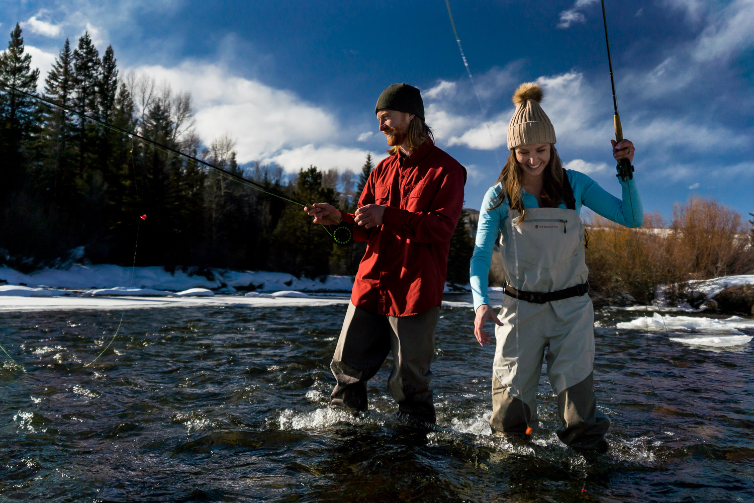 winter colorado engagement photos fly fishing in river with waders