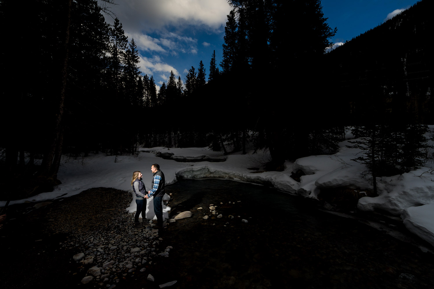 Winter Mountain Engagement Photos near creek with blue sky