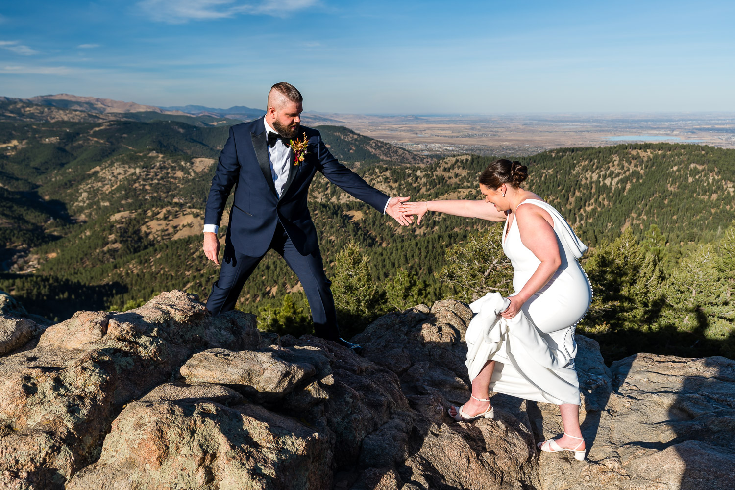 bride and groom climbing on rocks before flagstaff house wedding